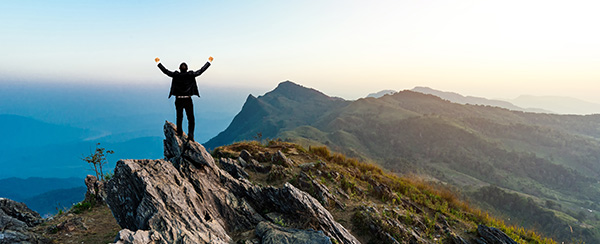 A person standing on top of a mountain with their arms in the air.